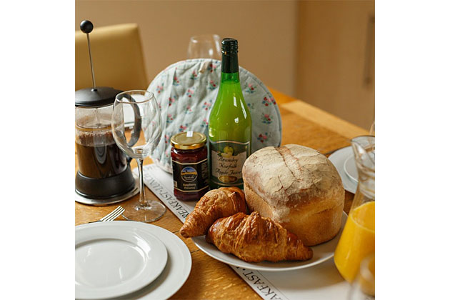 Lapwing Cottage's kitchen table set with coffee, bread, croissants…