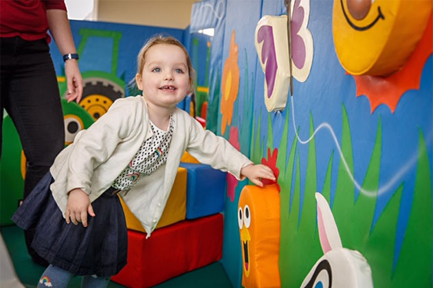 Smiling touch features in wall being tried out by young girl in soft play area