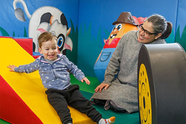 Slide in the soft play area, with happy user, smiling mum looking on